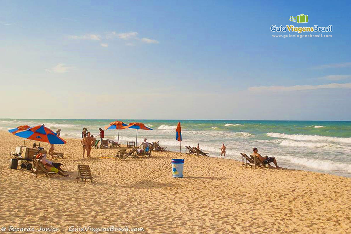 Imagem de pessoas com cadeiras e guarda sol próximo ao mar da Praia do Futuro.